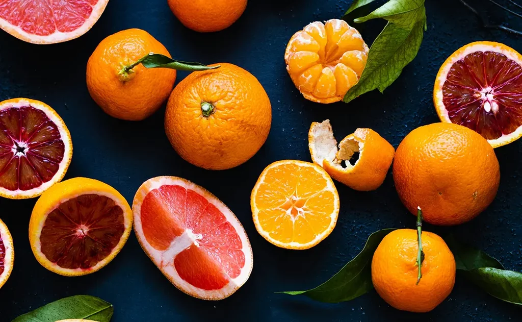 Assorted citrus fruits on dark background.