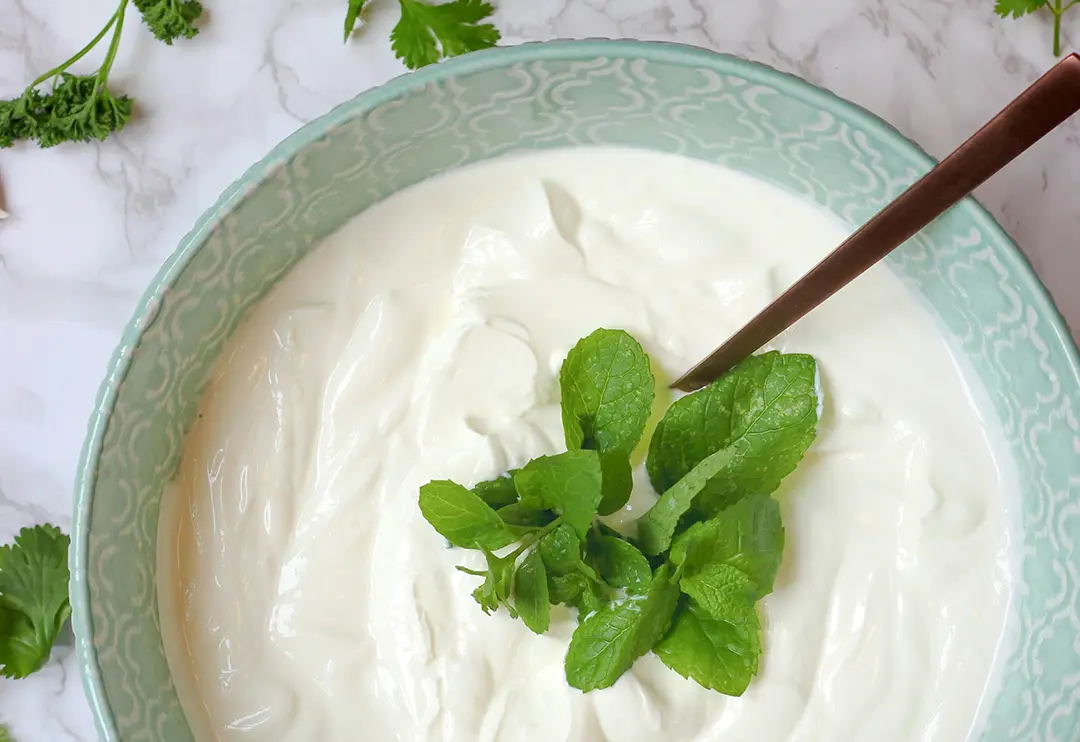 Bowl of yoghurt with mint leaves.