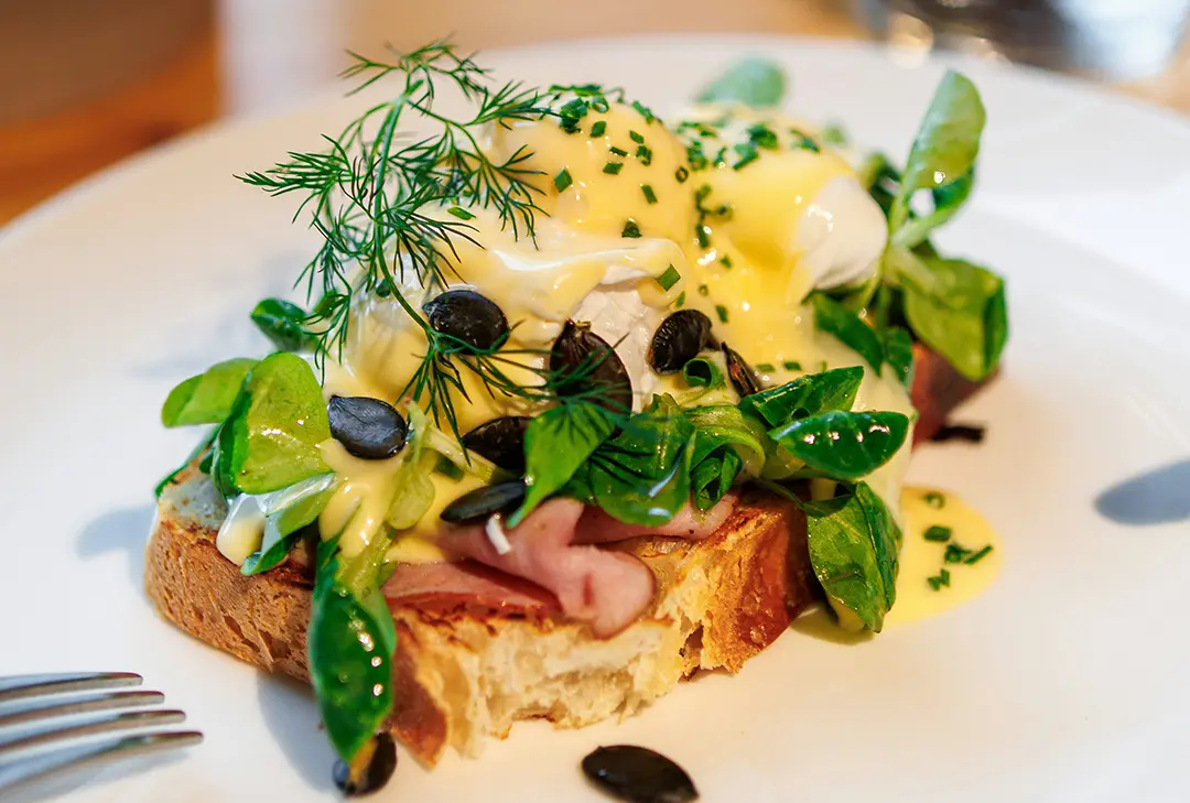 Eggs benedict with ham and greens on toast