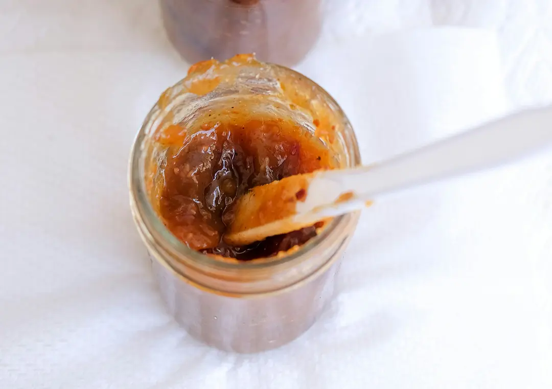 Open jar of chutney with spoon inside