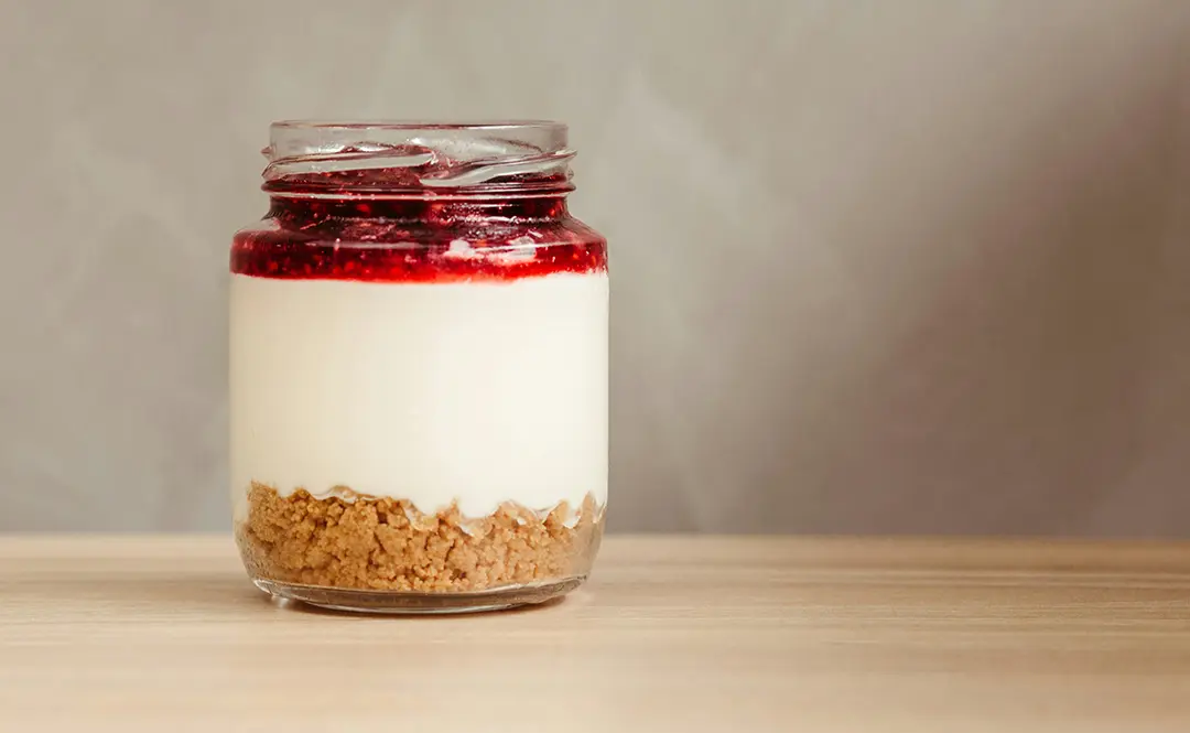 Layered cheesecake in a jar with fruit topping.