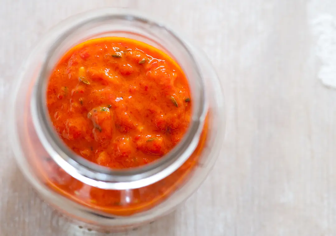 Jar of red pepper sauce on table
