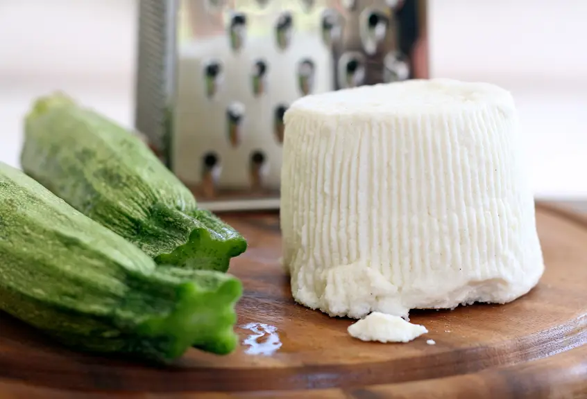 Courgettes and cheese with grater on wooden board