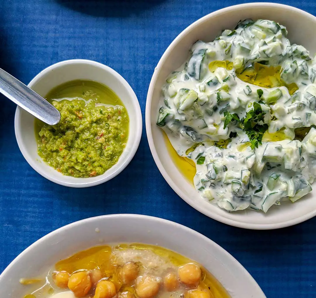 Cucumber salad, dip, chickpeas on blue table