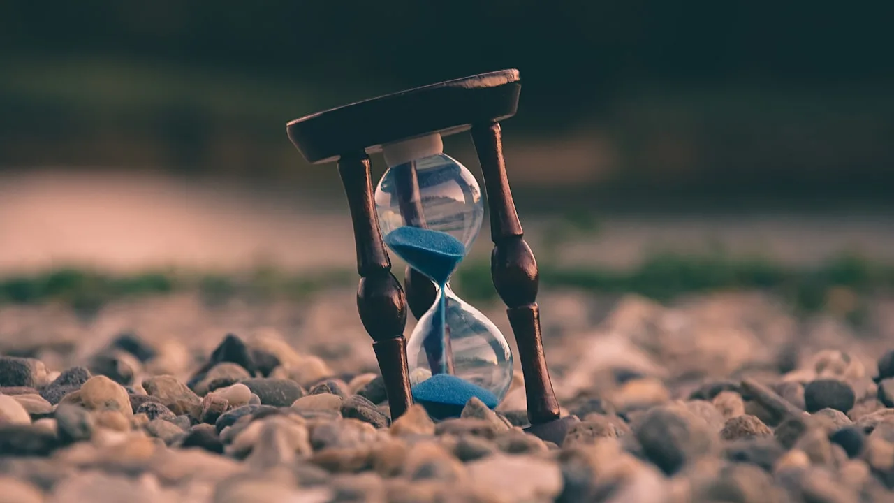 Hourglass on pebbles with blue sand