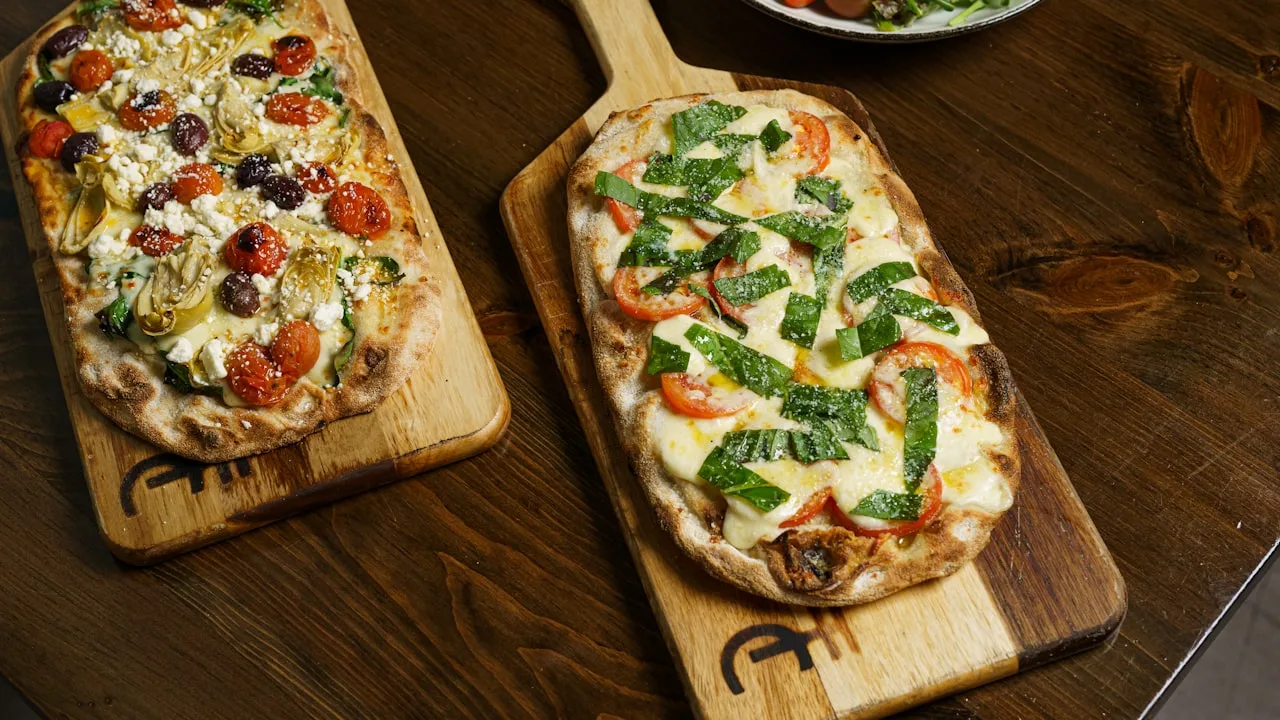 Two flatbreads with toppings on boards