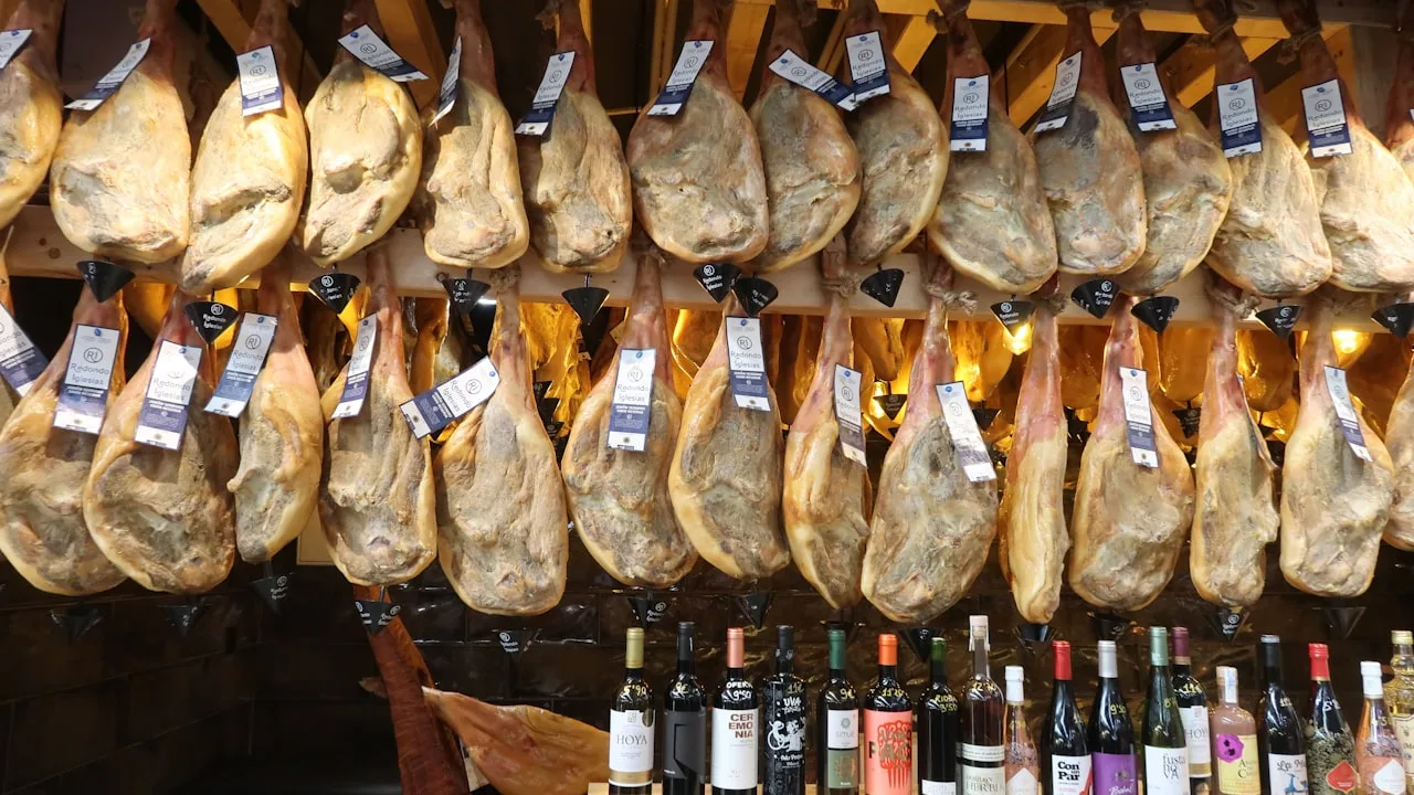 Hanging cured hams above wine bottles