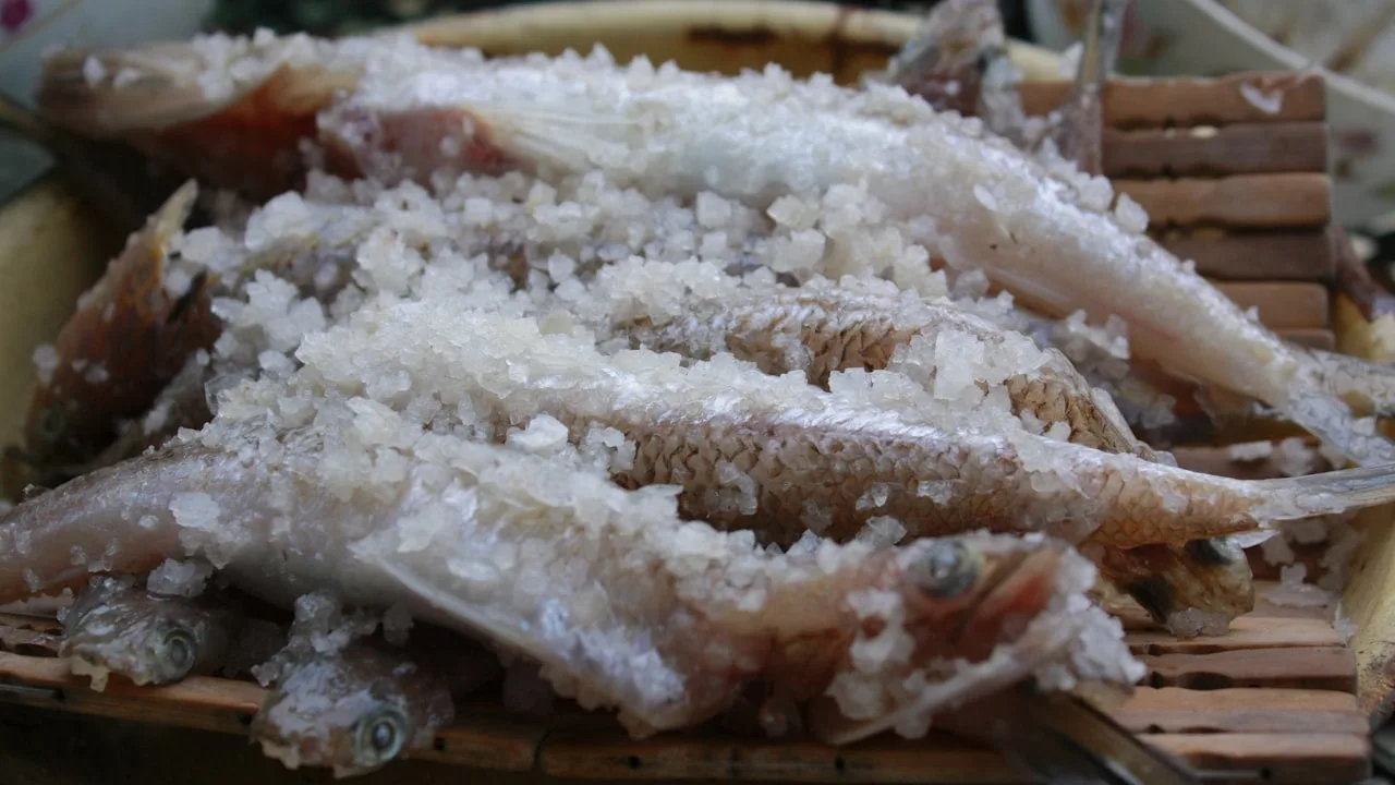 Salt-covered fish on a wooden platter.