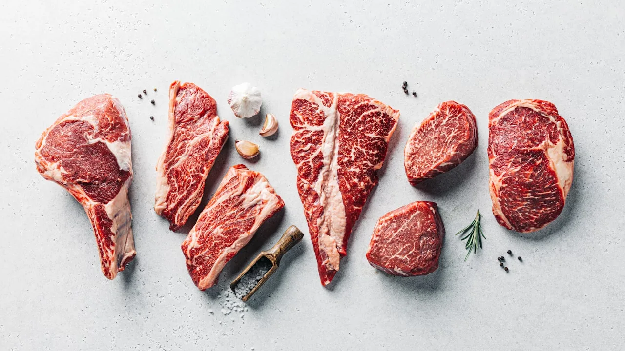 Assorted raw marbled beef steaks with garlic and rosemary